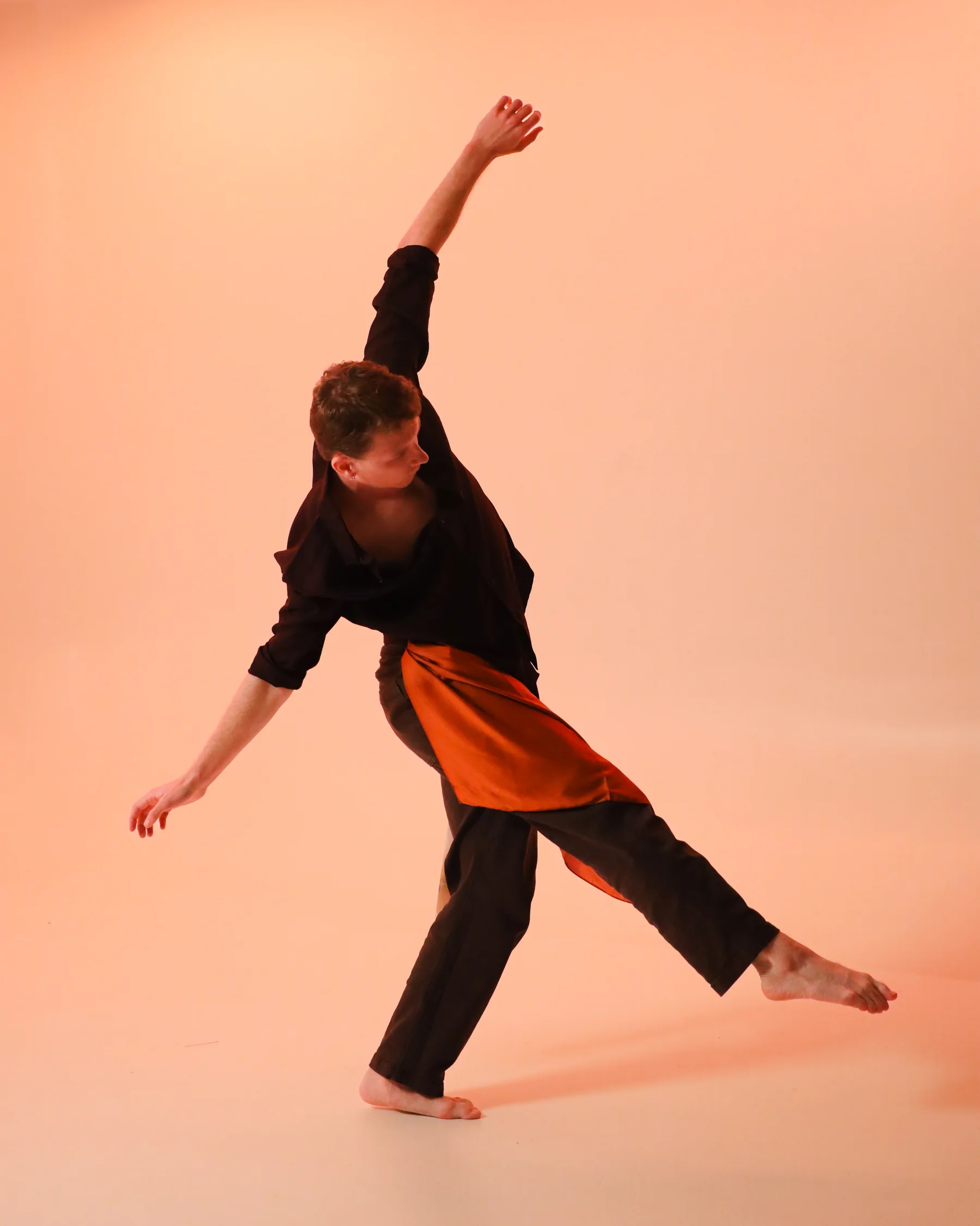 A dancer in dark trousers sweeping through a low, extended phrase