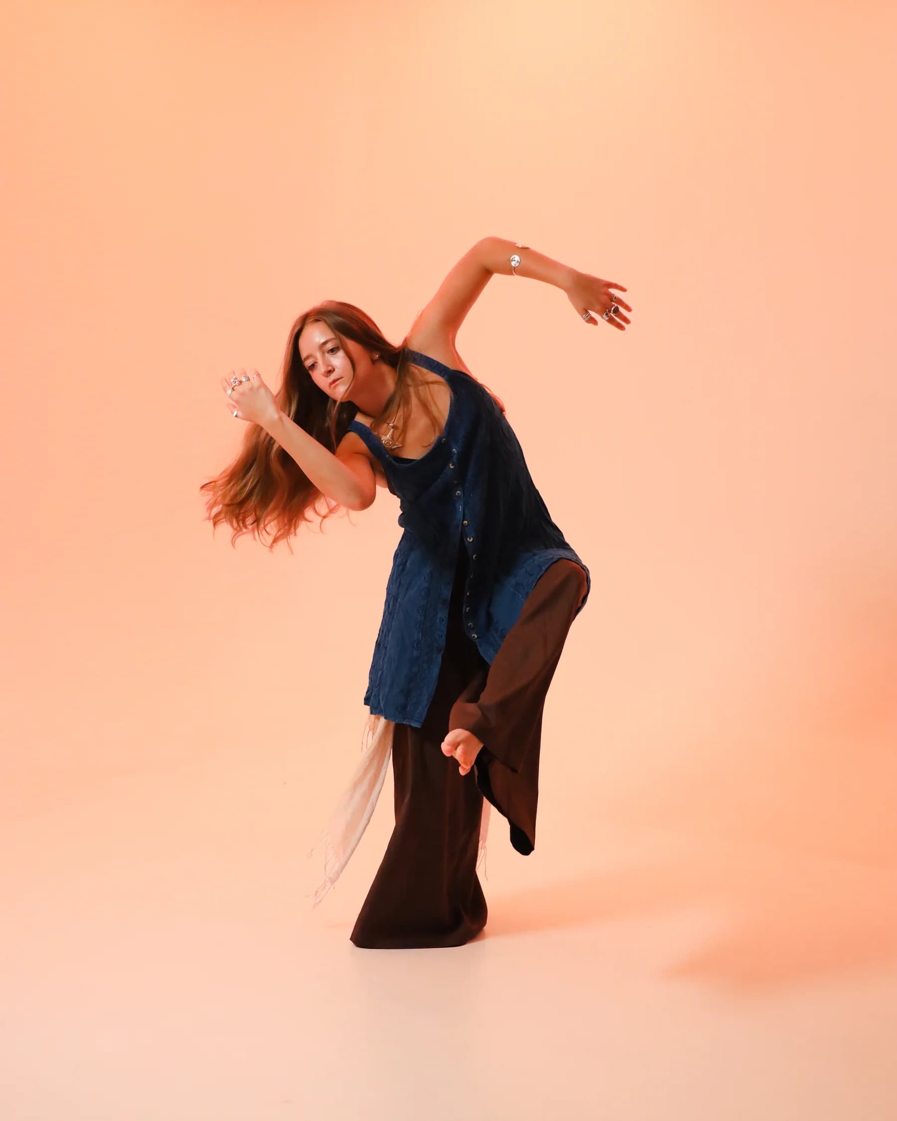 A dancer in blue arching sideways with one arm curved overhead