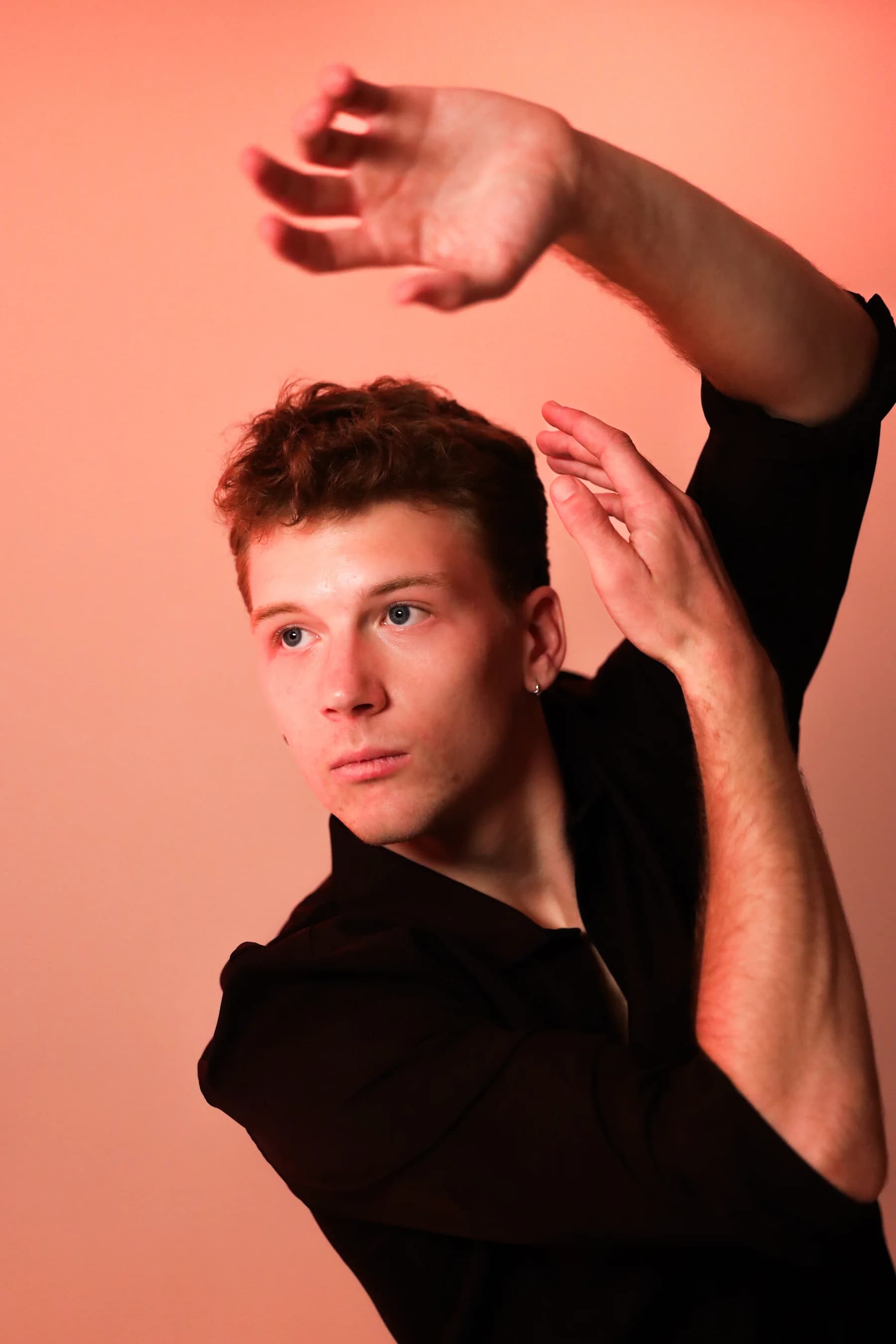 Expressive studio portrait of a dancer with both arms curved overhead