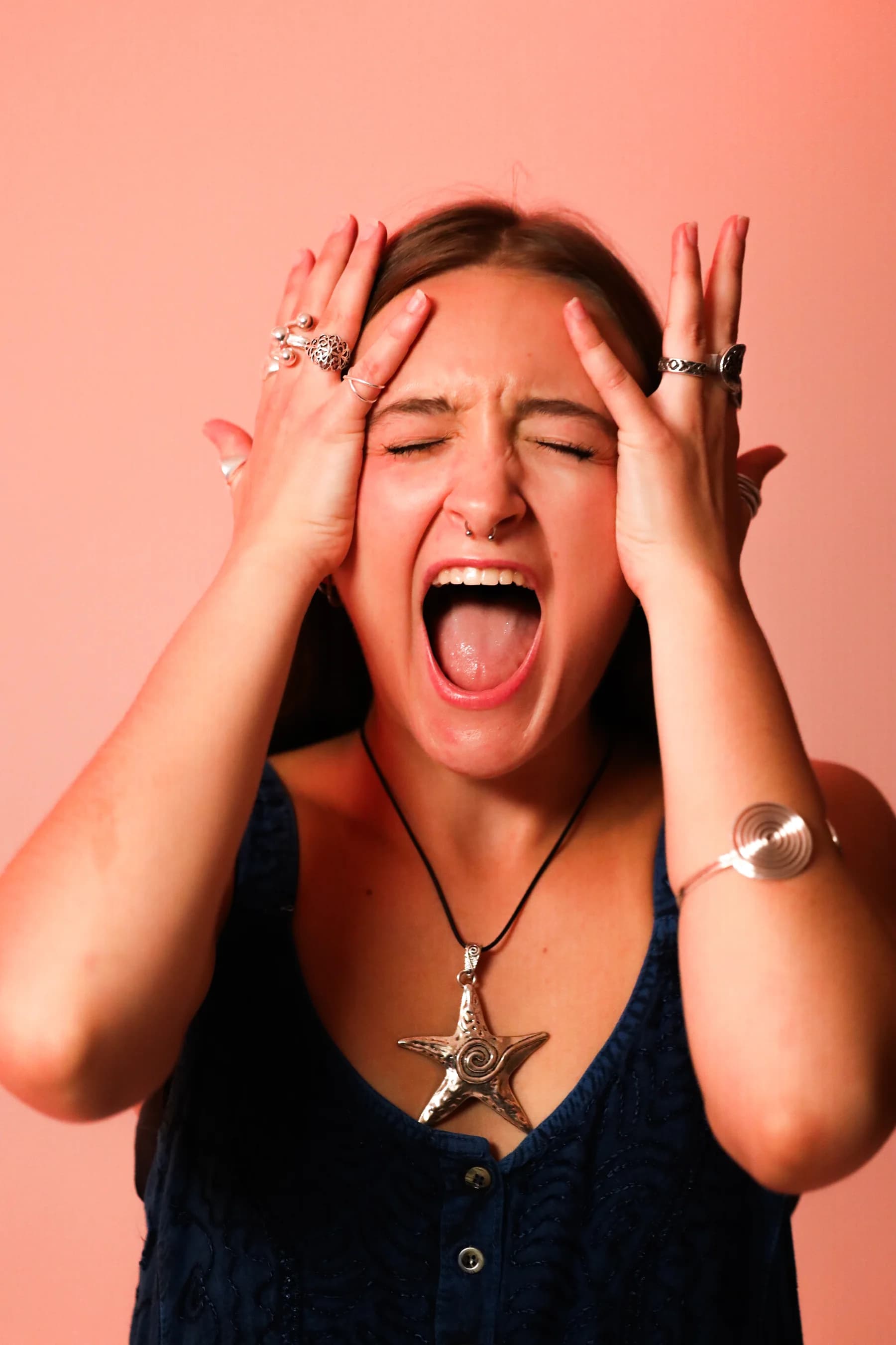 Expressive studio portrait of a dancer laughing with both hands beside her face